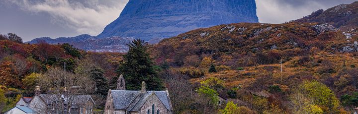 Blick auf einen kleinen Ort mit dem großen Berg Suilven.