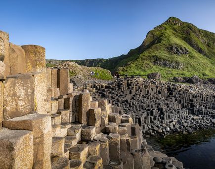 Giants Causeway Stones Mit grünen Bergen im Hintergrund