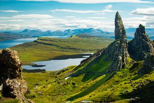 Felsige und grüne Landschaft auf der Insel Isle of Skye mit Gewässern und vielen Bergen im Hintergrund