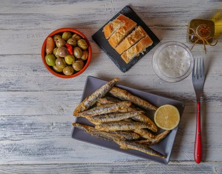 Tapas. Ein kleiner Teller mit einigen kleinen Köstlichkeiten. Daneben Brot, Oliven, Dips und eine Gabel