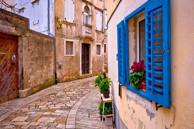 Eine enge Gasse mit Gebäuden und einem blauen Fenster.