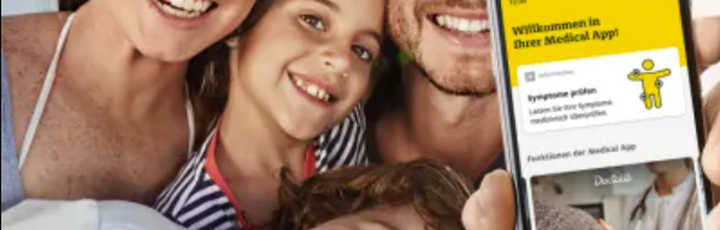 Glückliche Familie macht ein Selfie, im Vordergrund Smartphone mit geöffneter ADAC Medical App, Symbol für digitale Sicherheit.