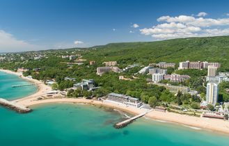 Eine Luftaufnahme eines Strandes mit goldenem Sand, türkisfarbenem Wasser und Hotels.