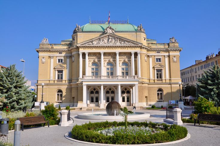 Blick auf die Front des Nationaltheaters in Rijeka. Imposantes Gebäude, blauer Himmel im Hintergrund.