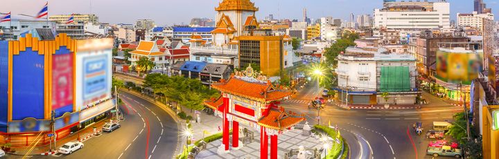 Das hell erleuchtete chinesische Tor am Odeon Circle in Bangkoks Stadtteil Chinatown bei Dämmerung.
