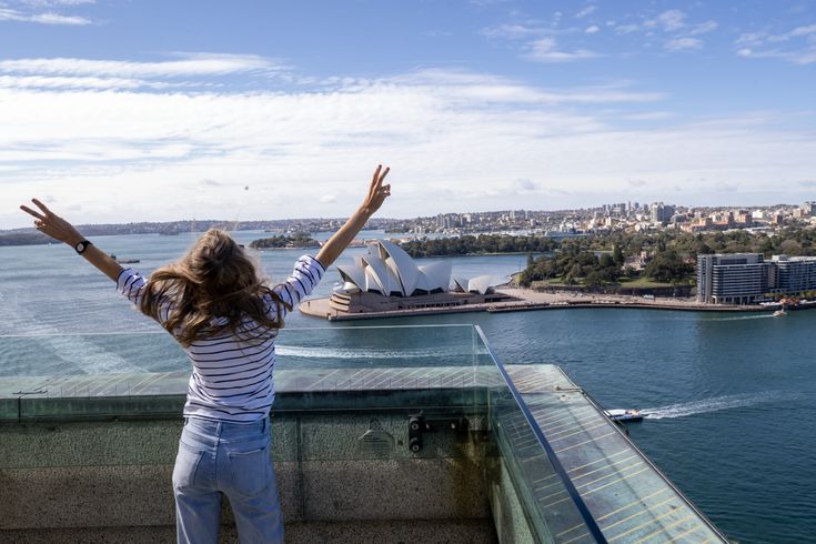 Frau schaut auf Sidney und streckt ihre Arme nach oben