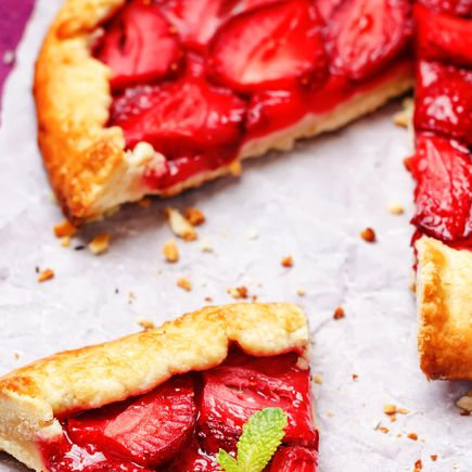 Eine Scheibe eines Erdbeerkuchens mit frischen Erdbeeren, die auf einer weißen Platte liegen. Der Kuchen ist in Stücke geschnitten und teilweise gegessen.