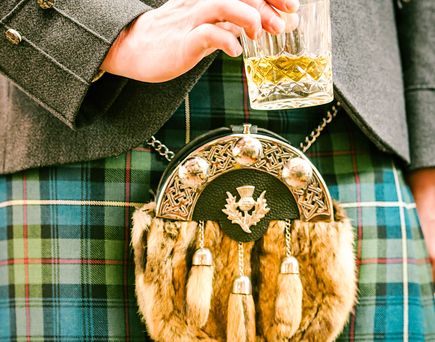 Eine Hand hält ein Glas Whisky.