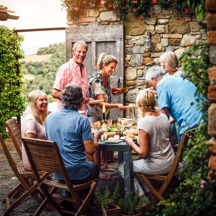 Ferienhaus Italien Urlaub Gruppe von Menschen an gedecktem Tisch im Freien