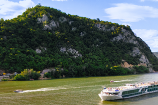 Flusskreuzfahrtschiff auf der Donau mit Bergen im Hintergrund