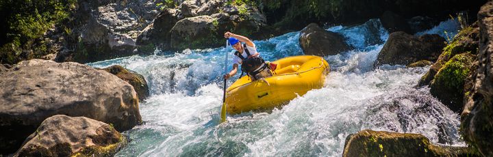 Person fährt mit dem Raft einen Fluss herunter 