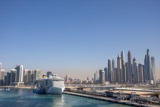 Kreuzfahrtschiff im HAfen von Dubai mit Skyline im Hintergrund