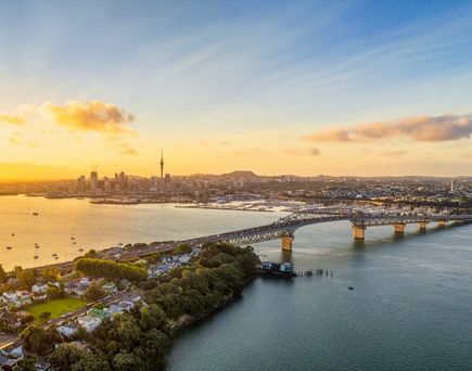 Eine weite Aufnahme des Waitemata Harbour in Auckland, Neuseeland, mit zahlreichen Segelbooten auf dem Wasser und der Skyline der Stadt im Hintergrund.