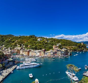 Luftaufnahme der malerischen Hafenstadt Portofino in Ligurien, Italien, mit bunten Häusern und Yachten im klaren Wasser.