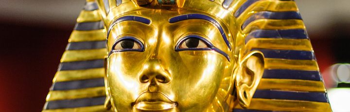 Eine Nahaufnahme zeigt die goldene, mit blauen Lapislazuli-Streifen verzierte Totenmaske des Pharaos Tutanchamun.