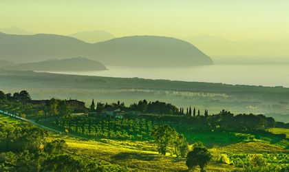 Eine weite Landschaft mit grünen Hügeln und dem Meer.