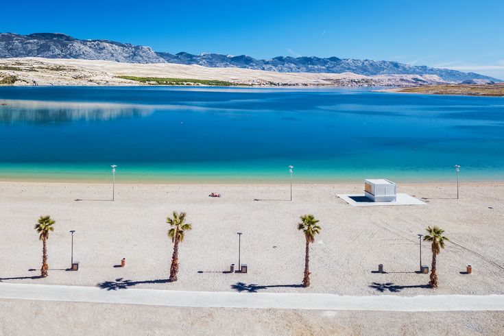 Ein Sandstrand mit Strandliegen und türkisfarbenem Wasser.