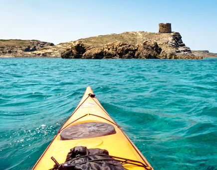 Eine Person in einem gelben Kajak auf türkisfarbenem Wasser.