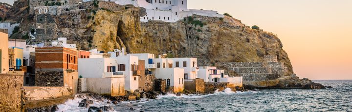 Schroffe Küste, davor kleine Häuser, oben auf dem Felsen ist das Kloster zu sehen.