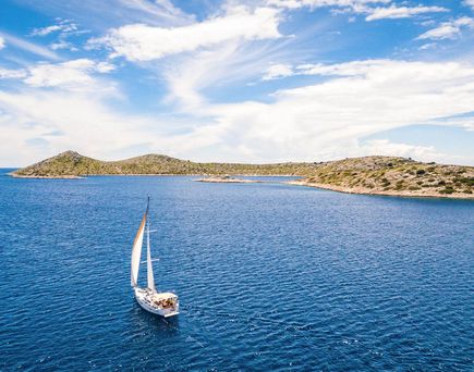 Ein Segelboot auf dem Meer mit einer Insel im Hintergrund.