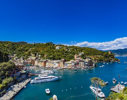 Luftaufnahme der malerischen Hafenstadt Portofino in Ligurien, Italien, mit bunten Häusern und Yachten im klaren Wasser.