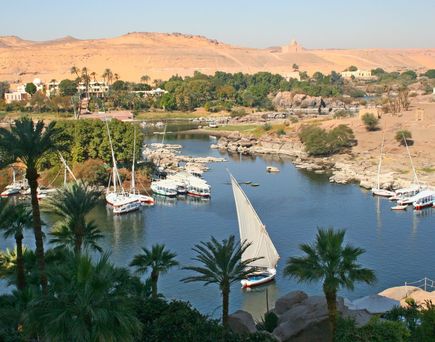 Unterschiedliche Boote auf dem Nil. Im Hintergrund die ägyptische Wüste