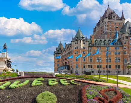 Blick auf das Chateaux Frontenac in Quebec City. Im Vordergrund Bulemenbeet mit Quebec Schriftzug