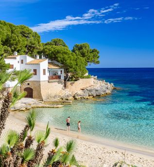 Blick auf die Bucht von Cala Ratjada, zwei Personen gehen ins Wasser
