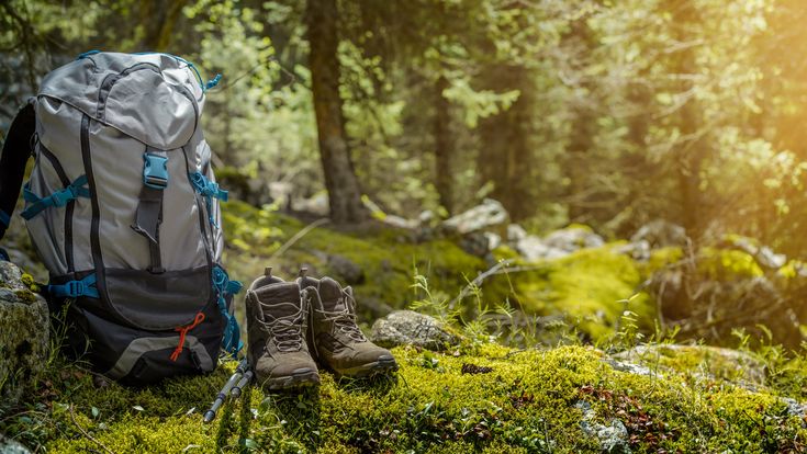 Rucksack und Wanderschuhe stehen im Wald 