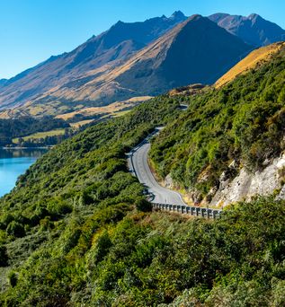 Eine Straße entlang dem Meer in Richtung Berge in Queenstown in Neuseeland