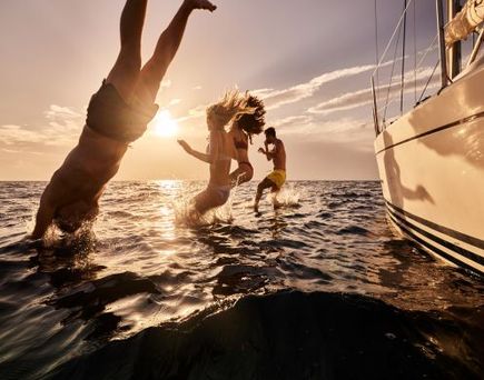 Eine Familie springt ins Wasser vom Boot aus.