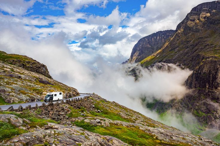 Grünes Tal mit Fluss und sprudelnden Wasserfällen in Norwegen, umgeben von hohen Bergen.