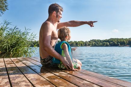 Vater sitzt mit Sohn auf Steg