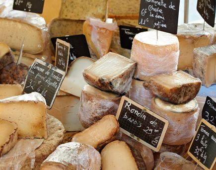 Eine Auswahl an verschiedenen Lebensmitteln, die auf einem Marktstand ausgestellt sind. Dazu gehören Oliven, Käse und andere lokale Spezialitäten, die appetitlich arrangiert sind.