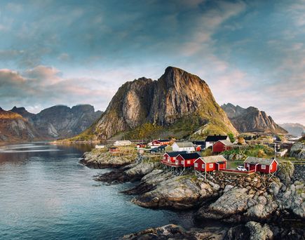 Eine malerische Küstenlandschaft der Lofoten in Norwegen mit einem Dorf und Bergen.
