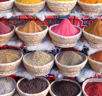 Eine Auswahl an farbenfrohen und aromatischen Gewürzen, präsentiert in geflochtenen Körben auf einem Markt in Ägypten.