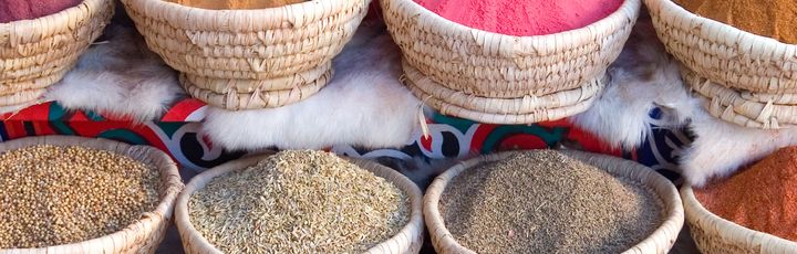 Eine Auswahl an farbenfrohen und aromatischen Gewürzen, präsentiert in geflochtenen Körben auf einem Markt in Ägypten.