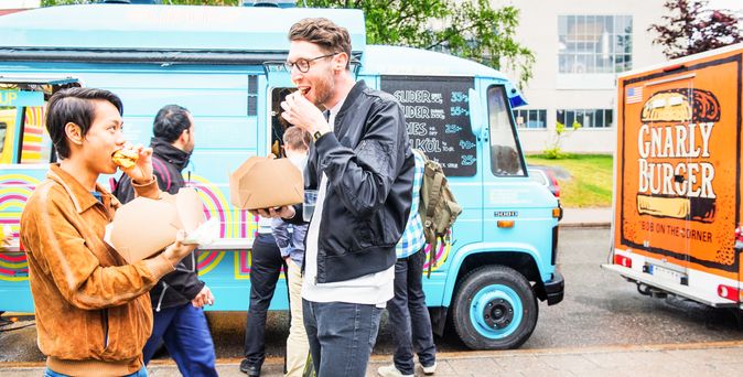 Zwei Personen stehen vor einem Food-Truck und bestellen etwas.