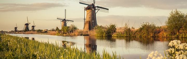 Eine Windmühle am Flussufer mit einem Boot.