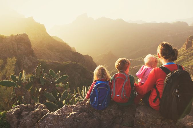Familie sitzt auf einem Felsen und blickt ins Tal