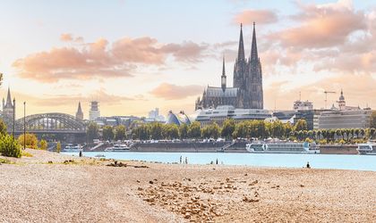 Eine Stadtansicht mit einem Dom und einem Fluss bei Sonnenuntergang.