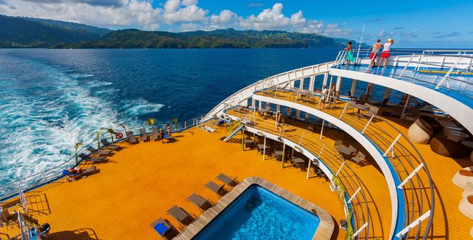 Ein Pool auf einem Kreuzfahrtschiff mit Blick auf das Meer und eine Küstenlandschaft.