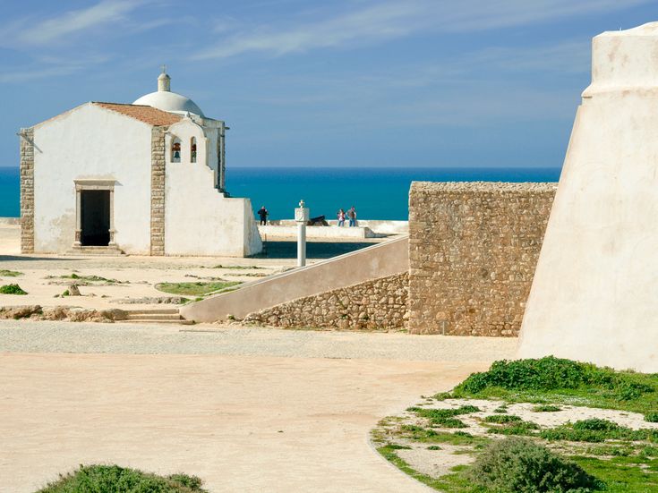 Eine weiße Kirche oder ein Gebäude auf einem Hügel mit Blick auf das Meer.