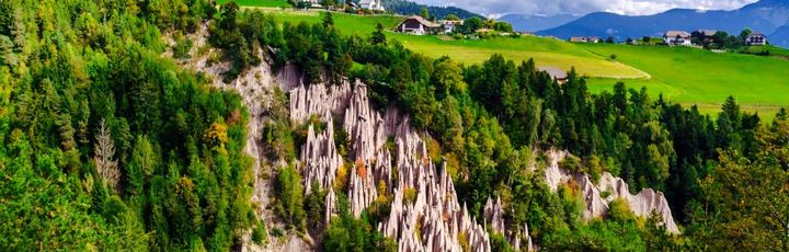 Eine Luftaufnahme von Erdpyramiden in Südtirol, umgeben von grüner Landschaft.
