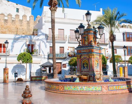 Eine historische Gasse mit einem Torbogen und Gebäuden in einer mediterranen Stadt.