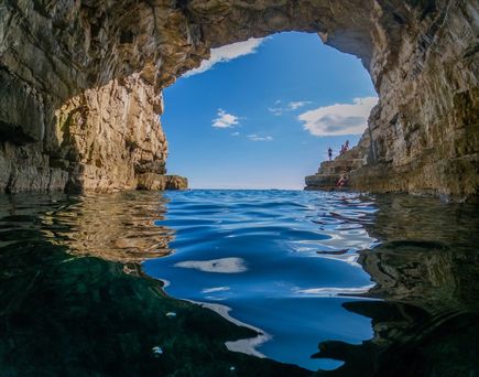 Eine natürliche Höhle mit einem Bogen und einem Strand.