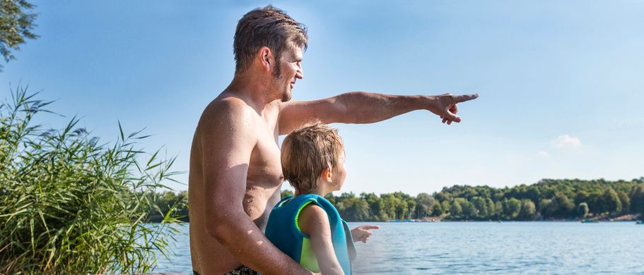 Vater sitzt mit Sohn auf Steg