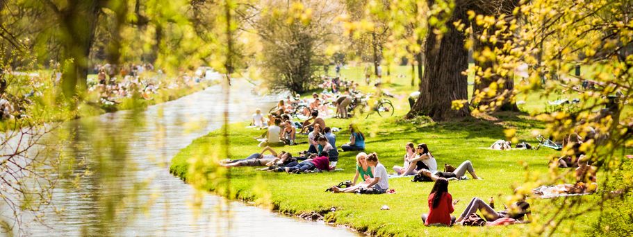 Städtereise München Urlaub Menschen im Park am Fluss
