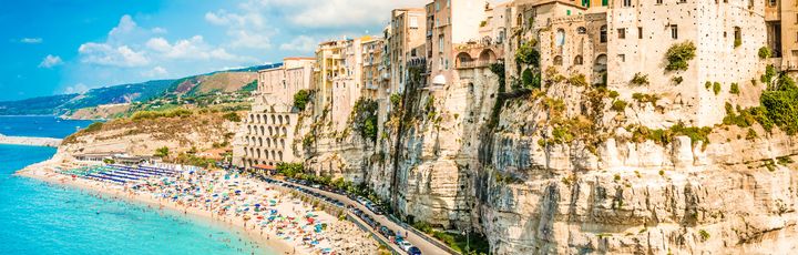 Ein Strand mit türkisfarbenem Wasser und einem felsigen Ufer.