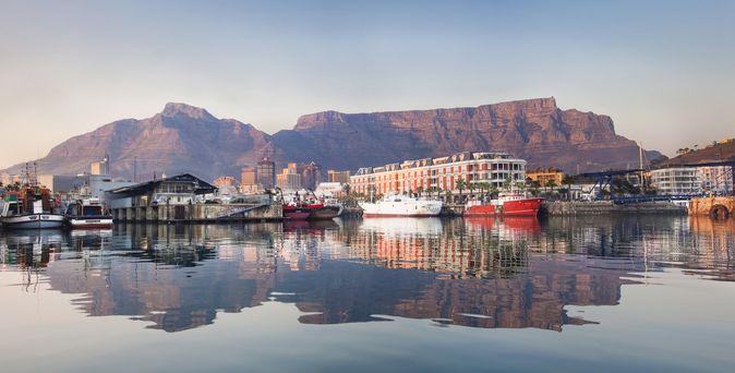 Eine Panoramaansicht der V&A Waterfront in Kapstadt, Südafrika, mit Yachten im Hafen und dem majestätischen Tafelberg im Hintergrund.